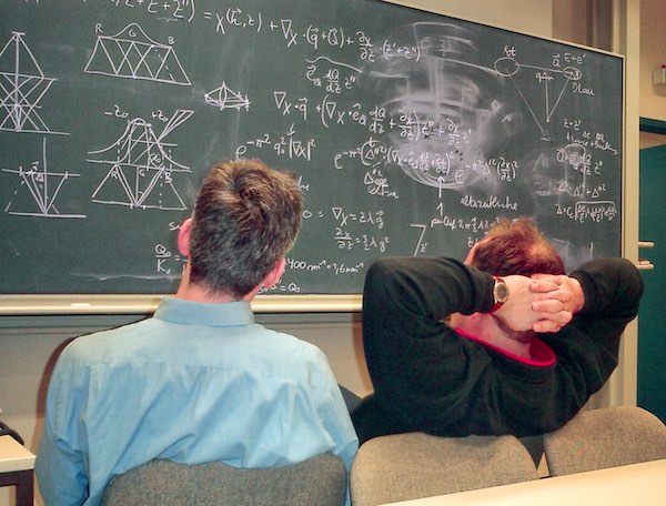 Dr. M.J.L und Dr. Andreas Thust bei einer wissenschaftlichen Erörterung an der Tafel